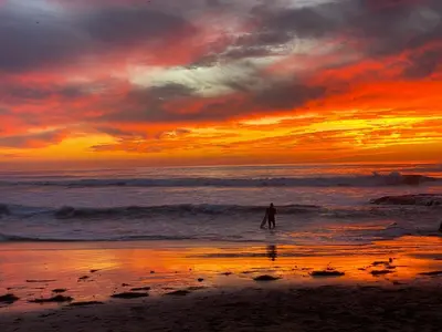 a person standing in the ocean at sunset at Modern 1 BR Cottage Steps 2Beach in San Diego