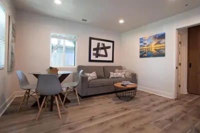 a living room with a couch and a table at Modern 1 BR Cottage Steps 2Beach in San Diego