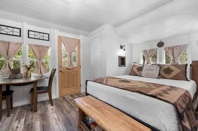 a bedroom with a bed and a table and windows at Julian Cafe Cottages With Breakfast At The Julian Cafe in Julian