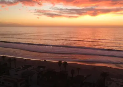 a sunset over the ocean with palm trees on the beach at Ocean, Bay, Downtown, and City view Condo, Few steps from the ocean in San Diego