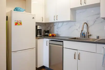a white kitchen with a sink and a refrigerator at Studio Apartment with Pool in the Heart of MissionValley in San Diego