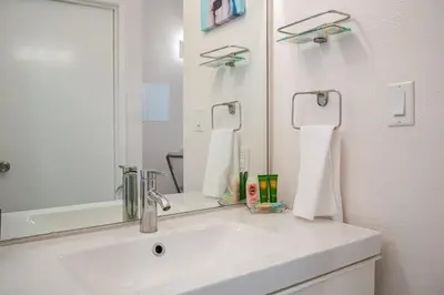 a white bathroom with a sink and a mirror at Studio Apartment with Pool in the Heart of MissionValley in San Diego