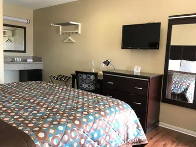 a hotel room with a bed and a flat screen tv at Berkshire Motor Hotel in San Diego