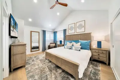 a bedroom with a large bed with blue pillows at Walk To The Waves Newport Beach House in Newport Beach