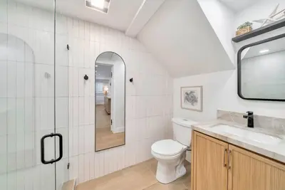a bathroom with a toilet and a sink and a mirror at Walk To The Waves Newport Beach House in Newport Beach