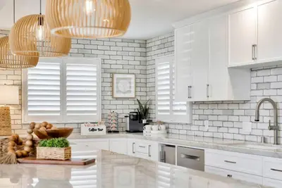 a white kitchen with white cabinets and a sink at Walk To The Waves Newport Beach House in Newport Beach