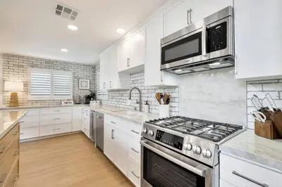 a kitchen with white cabinets and a stove top oven at Walk To The Waves Newport Beach House in Newport Beach