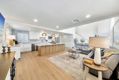 a living room with a couch and a kitchen at Walk To The Waves Newport Beach House in Newport Beach