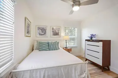 a white bedroom with a bed and a dresser at Coastal Palm Haven - With Hot Tub in Carlsbad