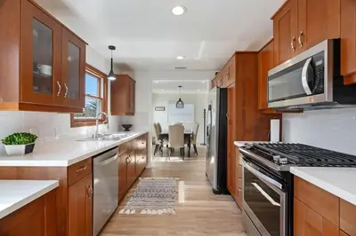 a kitchen with wooden cabinets and a stove top oven at Coastal Palm Haven - With Hot Tub in Carlsbad