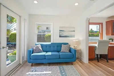 a blue couch in a living room with a kitchen at Coastal Palm Haven - With Hot Tub in Carlsbad