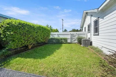 a yard next to a house with a hedge at Coastal Palm Haven - With Hot Tub in Carlsbad