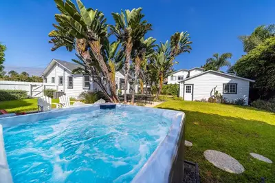 a large swimming pool in the yard of a house at Coastal Palm Haven - With Hot Tub in Carlsbad
