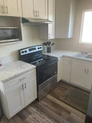 a kitchen with white cabinets and a black stove at Casa Mesa in San Diego
