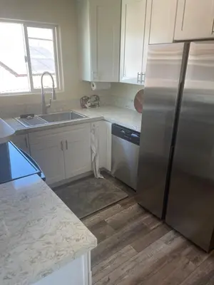 a kitchen with white cabinets and a stainless steel refrigerator at Casa Mesa in San Diego
