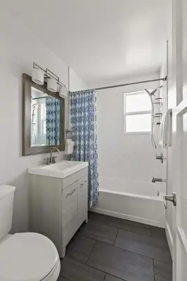 a white bathroom with a tub and a toilet and a sink at Beach Abode Walk to the Ocean in San Diego