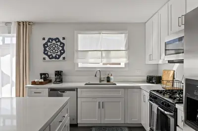 a white kitchen with white cabinets and a sink at 6 Bedroom Family Getaway Walk to Law Street Beach in San Diego