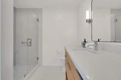 a white bathroom with a shower and a sink at Pacific Views Retreat - Rooftop Deck, Game Room, Fire Pit & Cozy Backyard! in San Diego