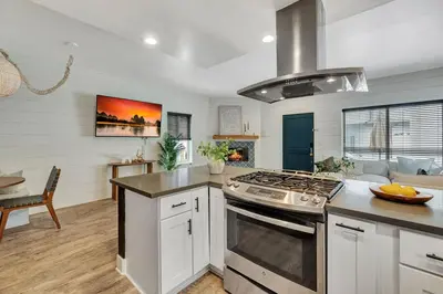 a kitchen with a stove top oven next to a living room at Steps to Lido Village and the Marina Heart of Lido Island WITH PARKING in Newport Beach