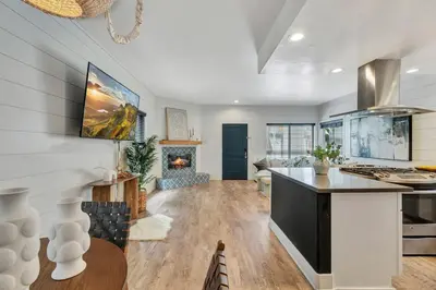 a kitchen and living room with a counter and a fireplace at Steps to Lido Village and the Marina Heart of Lido Island WITH PARKING in Newport Beach