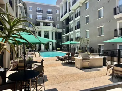 an outdoor patio with tables and chairs and a swimming pool at Allura Little Italy - 2 BR in Downtown's Top Spot in San Diego