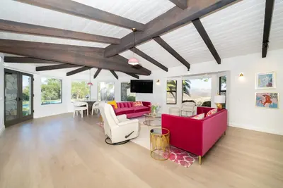 a living room with red couches and a table at Casa Via Zara - Sweeping Mountain Views with Pool in Fallbrook