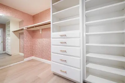a walk in closet with white shelves at Casa Via Zara - Sweeping Mountain Views with Pool in Fallbrook