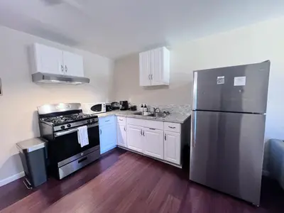 a kitchen with white cabinets and a stainless steel refrigerator at Calligraphy home with Private Deck near SDSU in San Diego