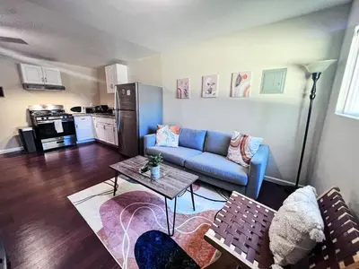 a living room with a blue couch and a table at Calligraphy home with Private Deck near SDSU in San Diego