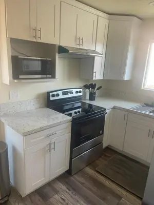 a kitchen with white cabinets and a black stove at Casa Mesa PLUS attached Studio & private Courtyard in San Diego