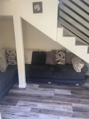 a blue couch with pillows sitting under a staircase at Casa Mesa PLUS attached Studio & private Courtyard in San Diego