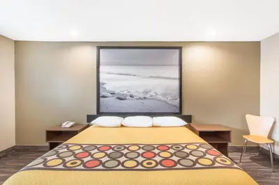 a hotel room with a bed with a picture on the wall at Super 8 by Wyndham National City Chula Vista in National City