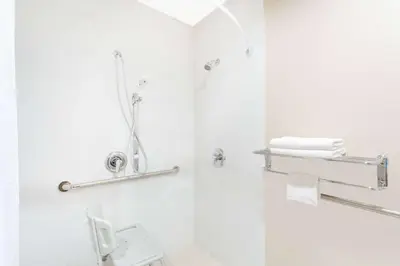a white bathroom with a shower and a toilet at Super 8 by Wyndham National City Chula Vista in National City