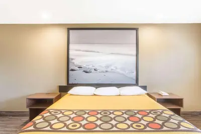 a room with a bed with a large picture on the wall at Super 8 by Wyndham National City Chula Vista in National City