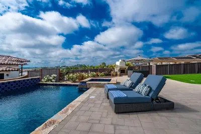 a backyard with a pool and a blue couch next to a swimming pool at Spanish Dream with Ocean Views in Encinitas