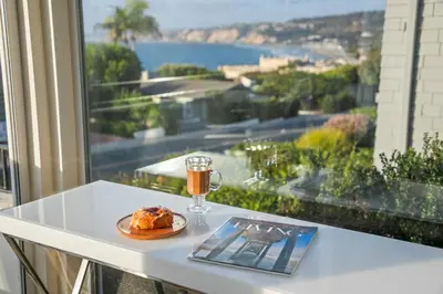 a table with a plate of food and a glass of drink at Sea Serenity Coastline Views and Pool in San Diego