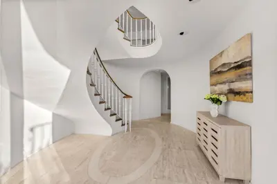 a staircase in a white room with a vase of flowers at Sea Serenity Coastline Views and Pool in San Diego