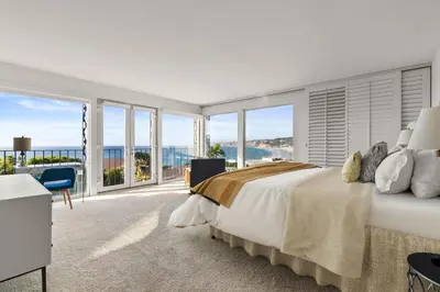 a bedroom with a large bed and large windows at Sea Serenity Coastline Views and Pool in San Diego