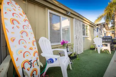 a surfboard sitting next to two chairs on a porch at Sandy Toes in San Diego