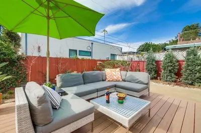 a patio with a couch and a green umbrella at Shores Perfection in San Diego