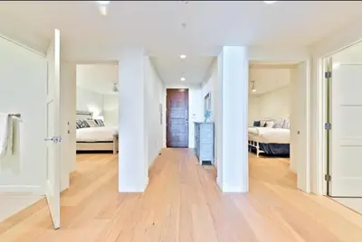 a large white room with two beds and a hallway at Blissful Retreat in San Diego