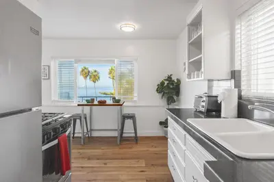 a kitchen with white cabinets and a sink and a table at Coastal Overlook in San Diego