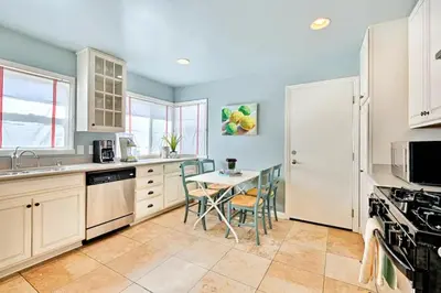 a kitchen with white cabinets and a table and chairs at Sandy Shores Beach House in San Diego