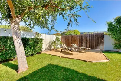 a patio with a bench and a tree in a yard at Sandy Shores Beach House in San Diego