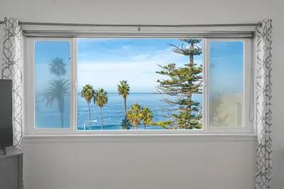 a window with a view of the ocean and palm trees at Coastal Sunsets in San Diego