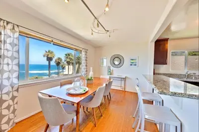 a dining room with a table and chairs and a view of the ocean at Coastal Sunsets in San Diego