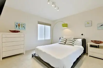 a white bedroom with a bed and a dresser at Village and Views in San Diego