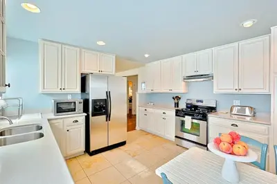 a kitchen with white cabinets and a plate of fruit on a table at Sand Patch in San Diego