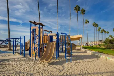 a playground with slides in the sand and palm trees at Sand Patch in San Diego