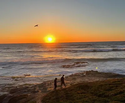 two people standing on the beach watching the sunset at Bonair Beauty in San Diego